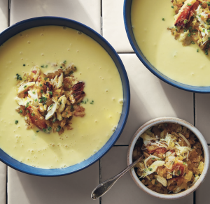 Two bowls of yellow0coloured corn soup with a pile of flaked crab meat in the middle.