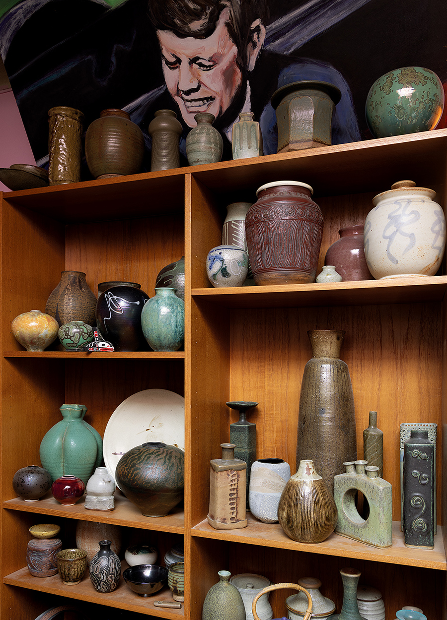 A wooden shelving unit filled with ceramic vases and other ceramic pieces