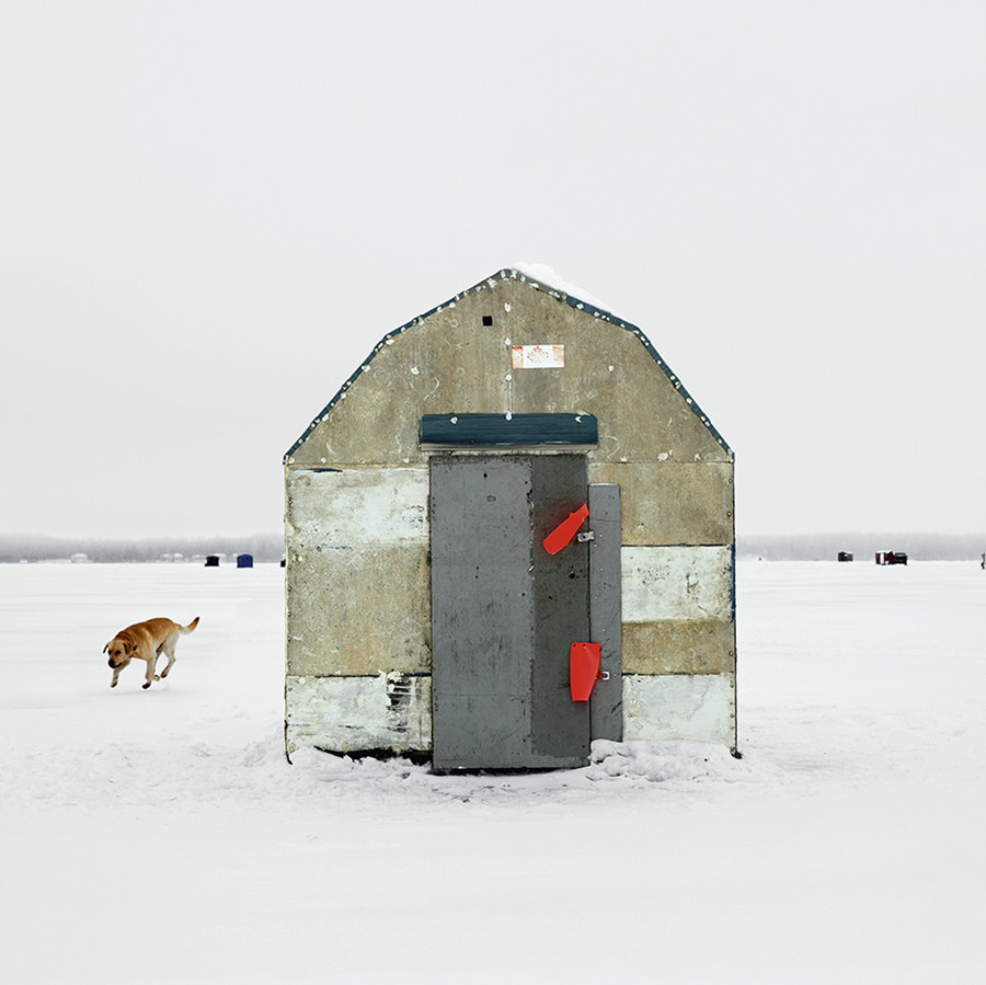 Ice fishing hut with dog beside it